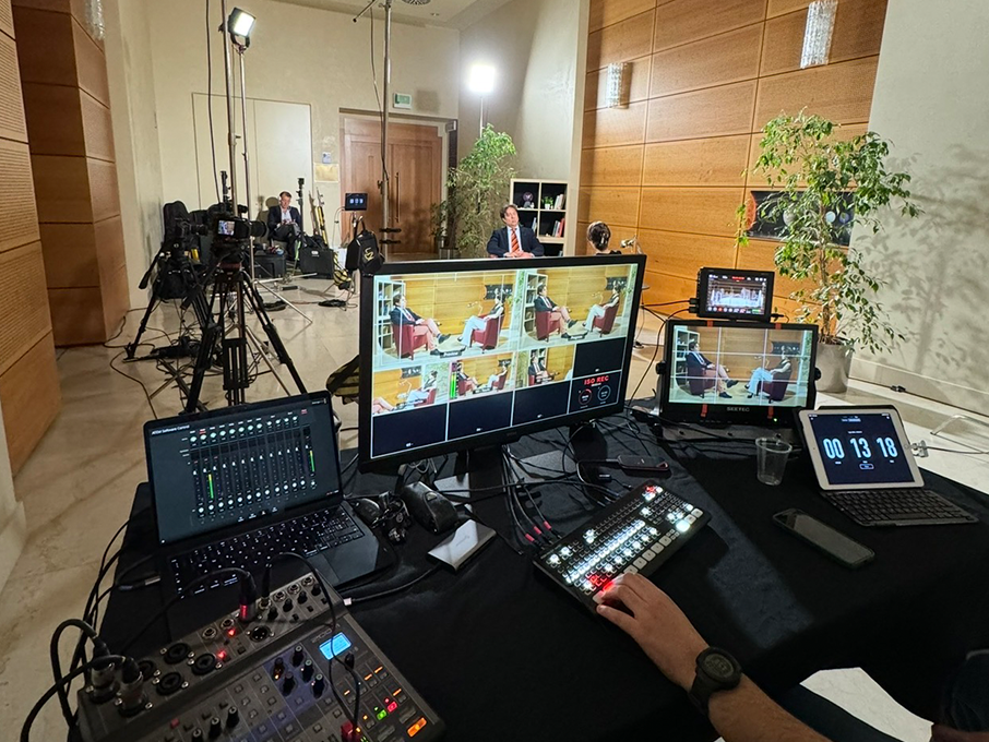 Backstage di una produzione multicamera: operatore alla regia con switcher ATEM, monitor multiview e camere su treppiede alle spalle